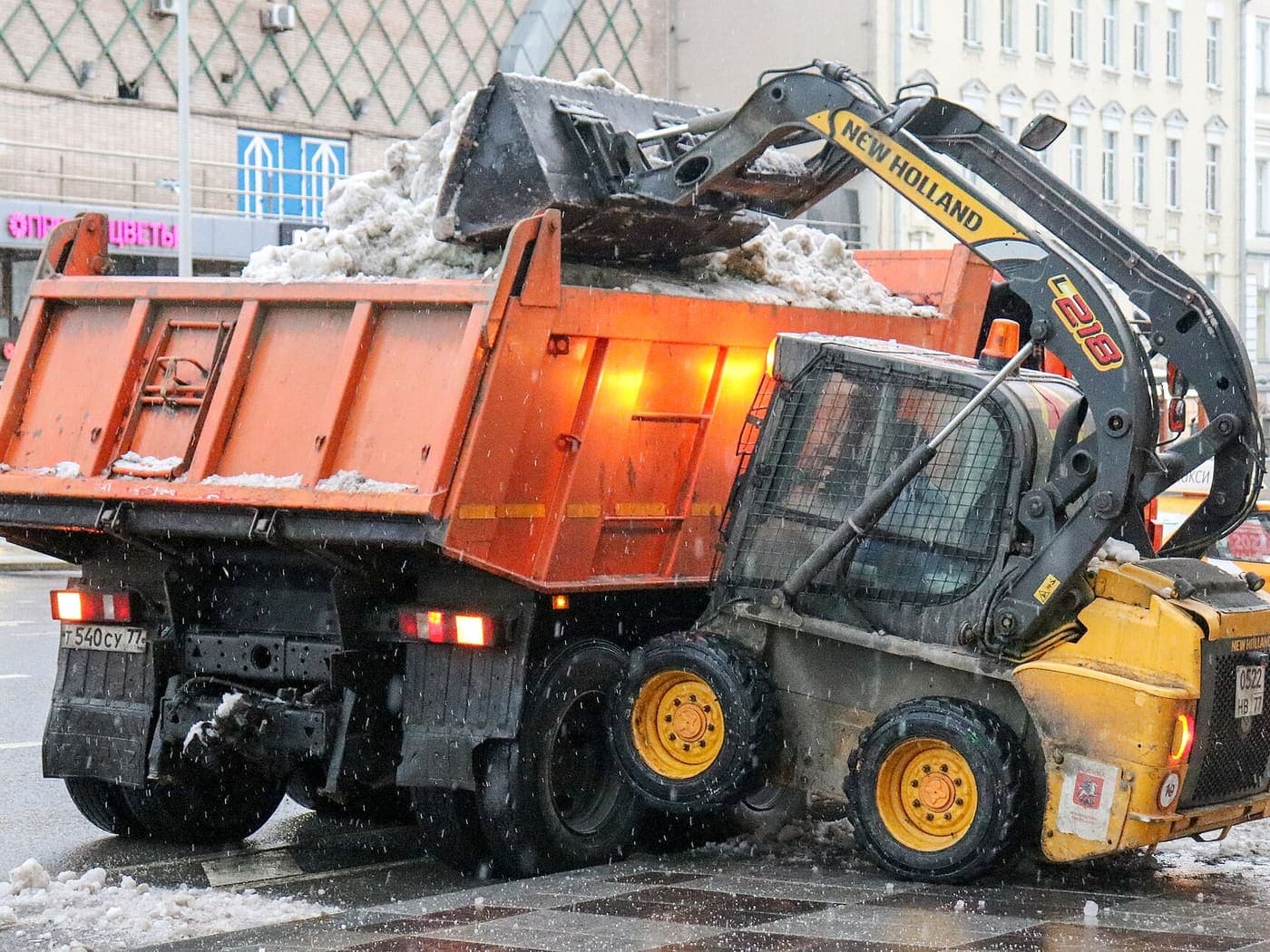 Уборка и вывоз снега — мини-погрузчик грузит снег в самосвал